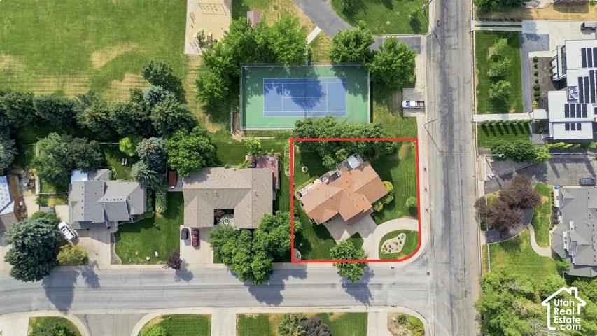 Corner lot with mature trees, circular driveway, and green lawn