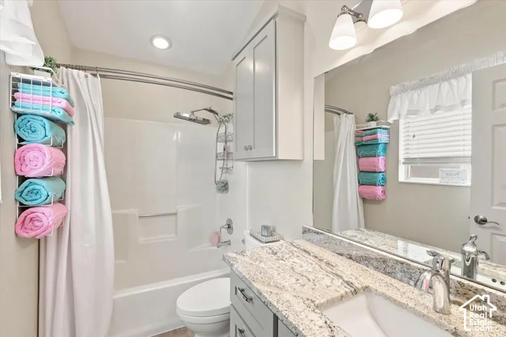 Bathroom featuring a vanity with a stone-finish countertop, undermount sink, and wall-mounted mirror