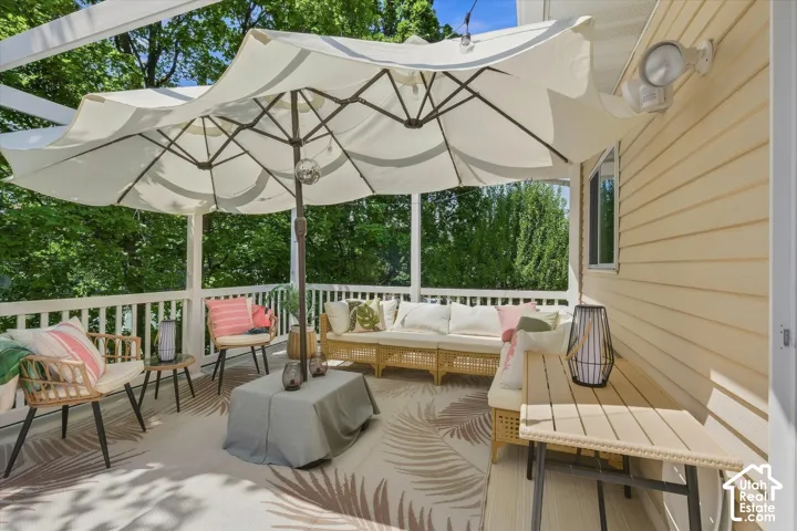 Expansive outdoor deck featuring a white railing, overhead pergola, and neutral-toned siding