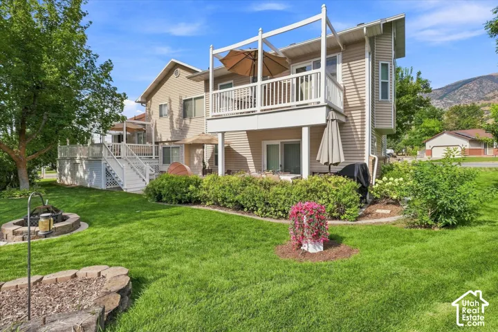 Expansive backyard with a manicured lawn, two-story deck, and a stone-lined fire pit
