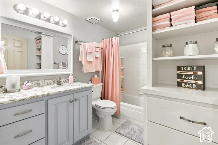Bathroom featuring a vanity with a light-colored countertop, built-in shelving, a shower-tub combination with white tile surround, and a wall-mounted light fixture