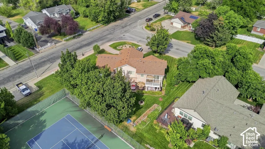 Property featuring a large tennis court, mature trees, manicured lawns, and a multi-level deck