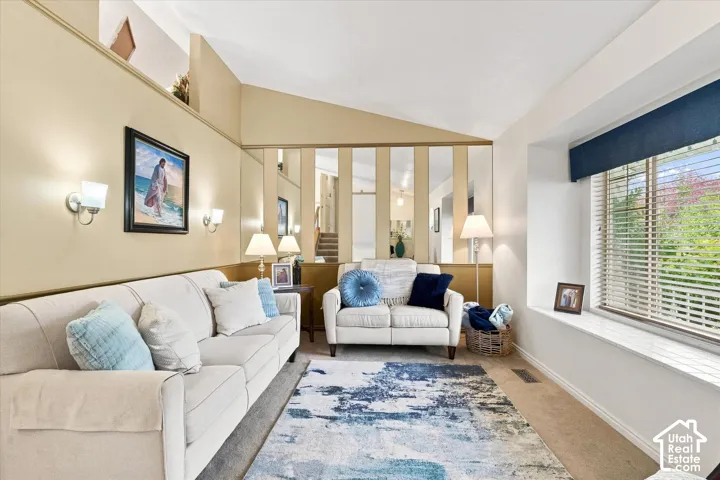 Vaulted ceiling, built-in window bench, wall sconces, mirrored wall paneling, and a large picture window