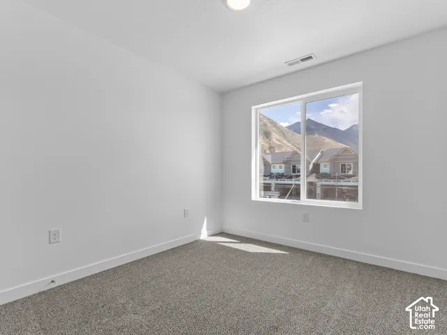 Bright interior with a window offering a mountain backdrop, complemented by clean white walls and a neutral carpet