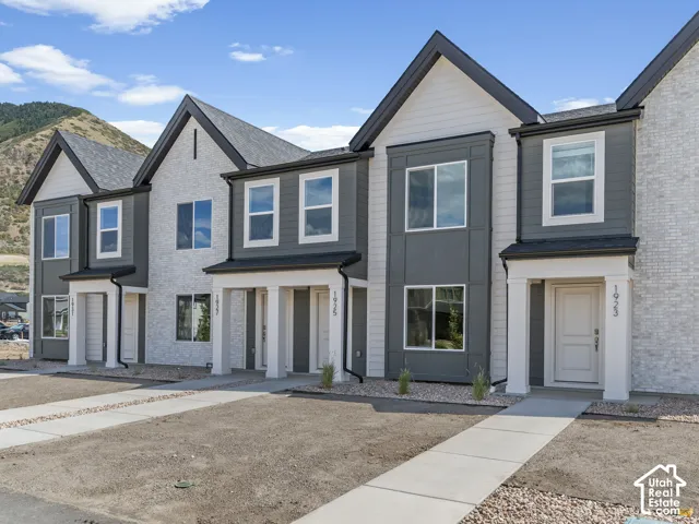 Townhome exterior featuring varied siding, white brick, dark-framed windows, and covered entryways