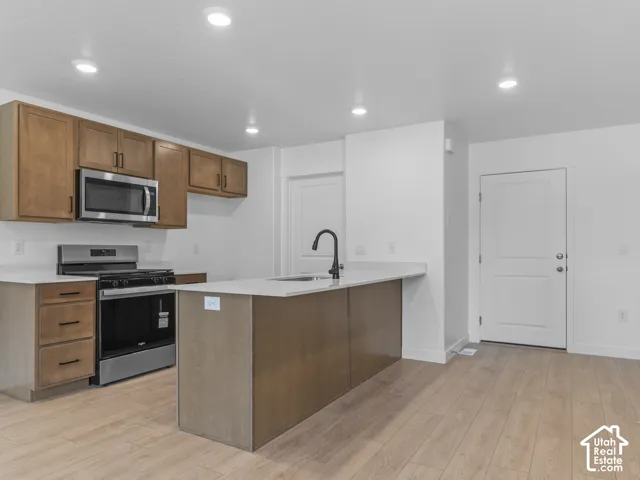 Modern kitchen featuring wood-finish flooring, recessed lighting, and stainless steel appliances