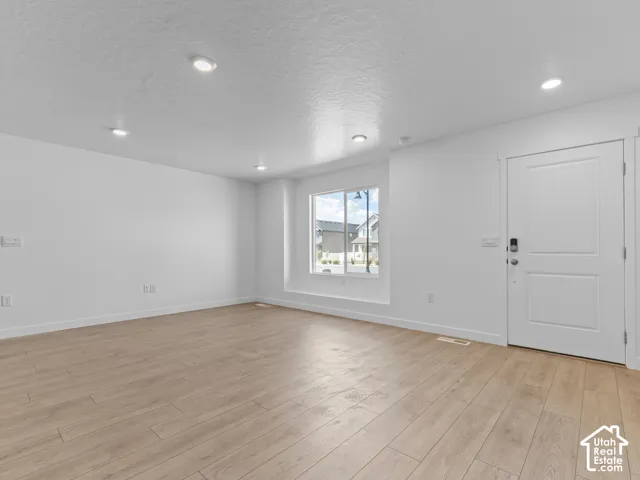 White interior walls, recessed ceiling lighting, wood-finish flooring, and a white entry door