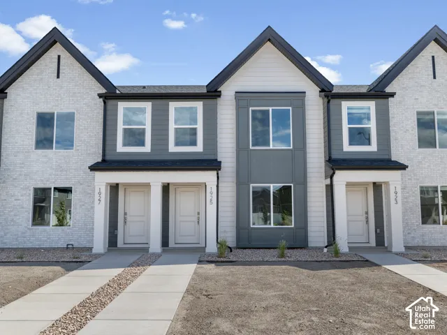 Modern townhome exterior featuring light brick, dark gray siding, and gabled roofs