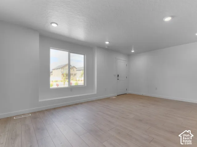 Recessed lighting, wood-finish flooring, white painted walls, white trim, and a white door