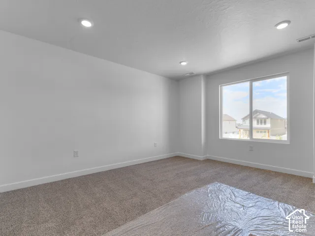 Recessed ceiling lighting, large window, neutral wall paint, white trim, and carpeted flooring