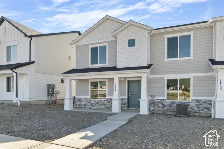 Light grey siding exterior with white trim, a covered front porch supported by columns, and a front entry door