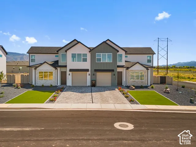Contemporary facade featuring mixed materials, attached garages, and a paver driveway