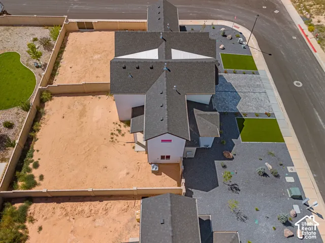 Dark shingle roof, white exterior walls, and a gravel front yard with artificial turf accents