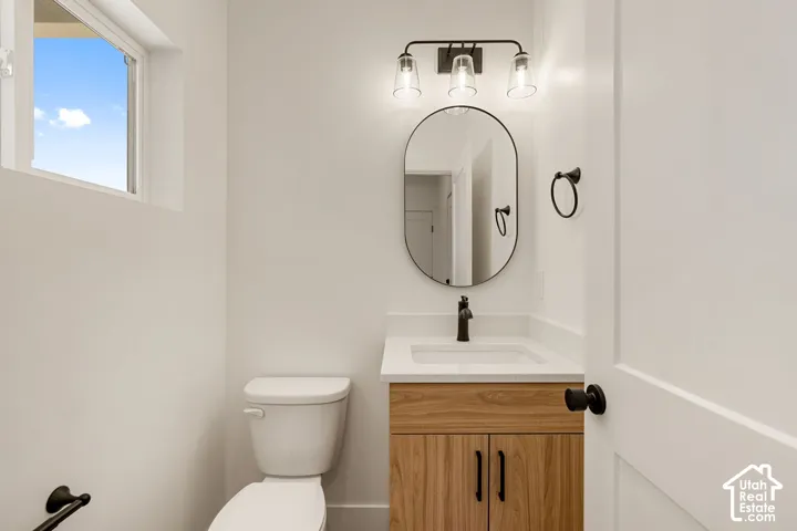 Modern vanity with wood-finish cabinetry, white countertop, and matte black hardware