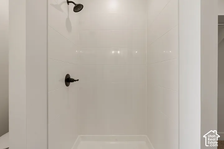 White tiled shower enclosure with a matte black shower head and control