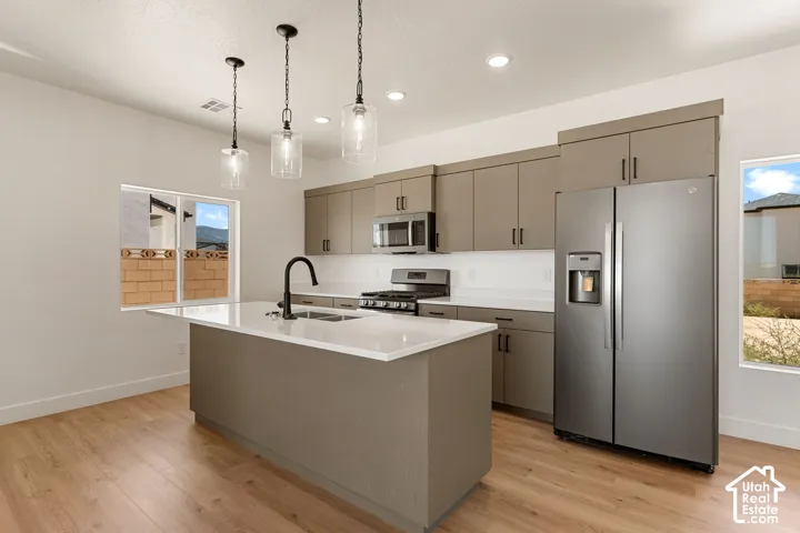Kitchen featuring a central island with countertop, stainless steel appliances, recessed lighting, and wood-finish flooring