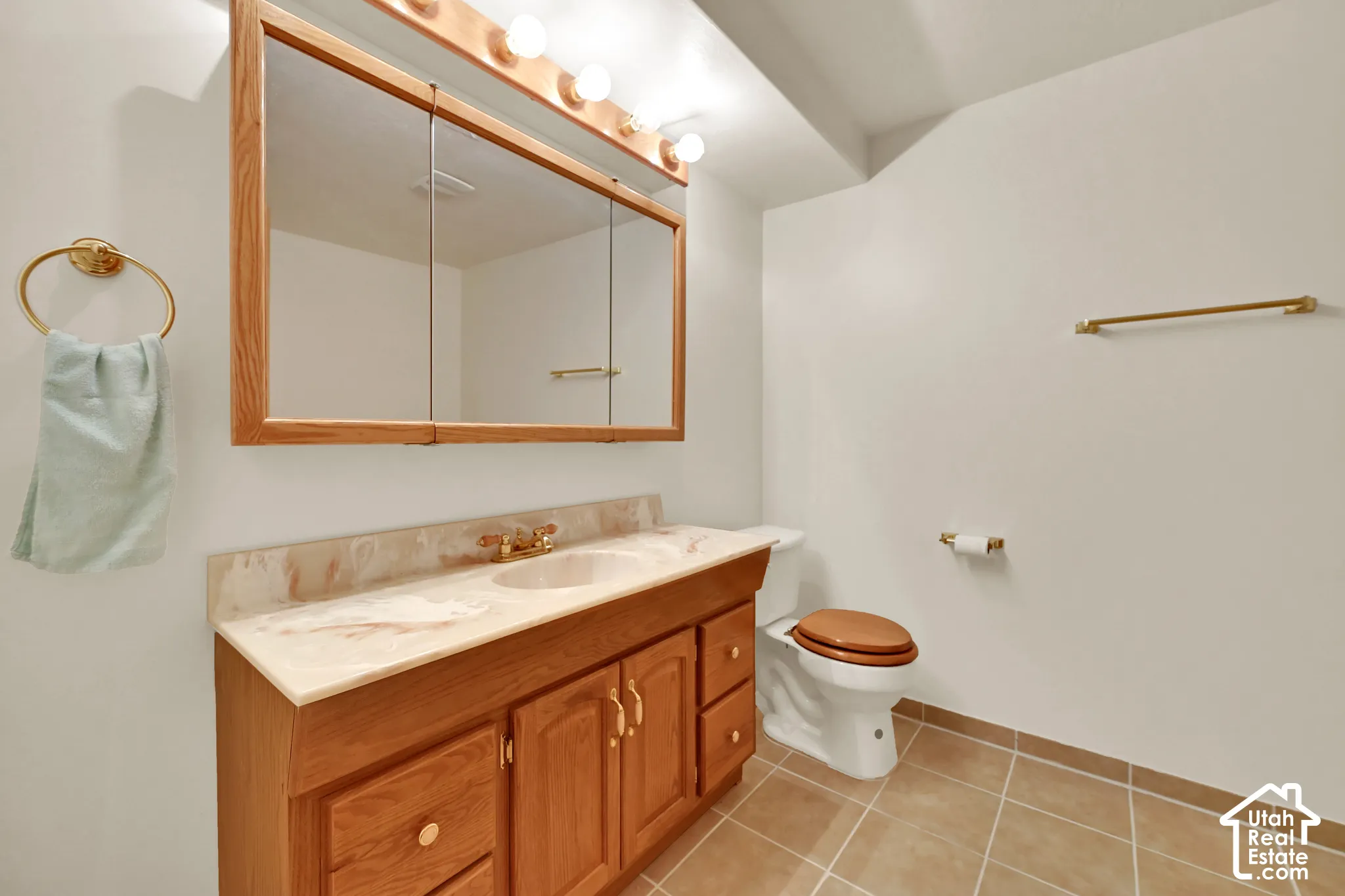 Bathroom featuring a wood-finish vanity with a light-toned countertop, dual inset sinks, a matching wood-finish medicine cabinet, and tile flooring