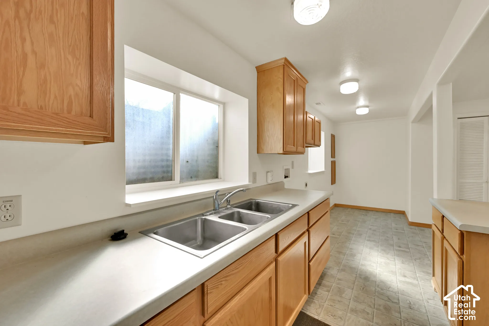 Kitchen featuring wood cabinetry, a double basin stainless steel sink, and light-toned countertops
