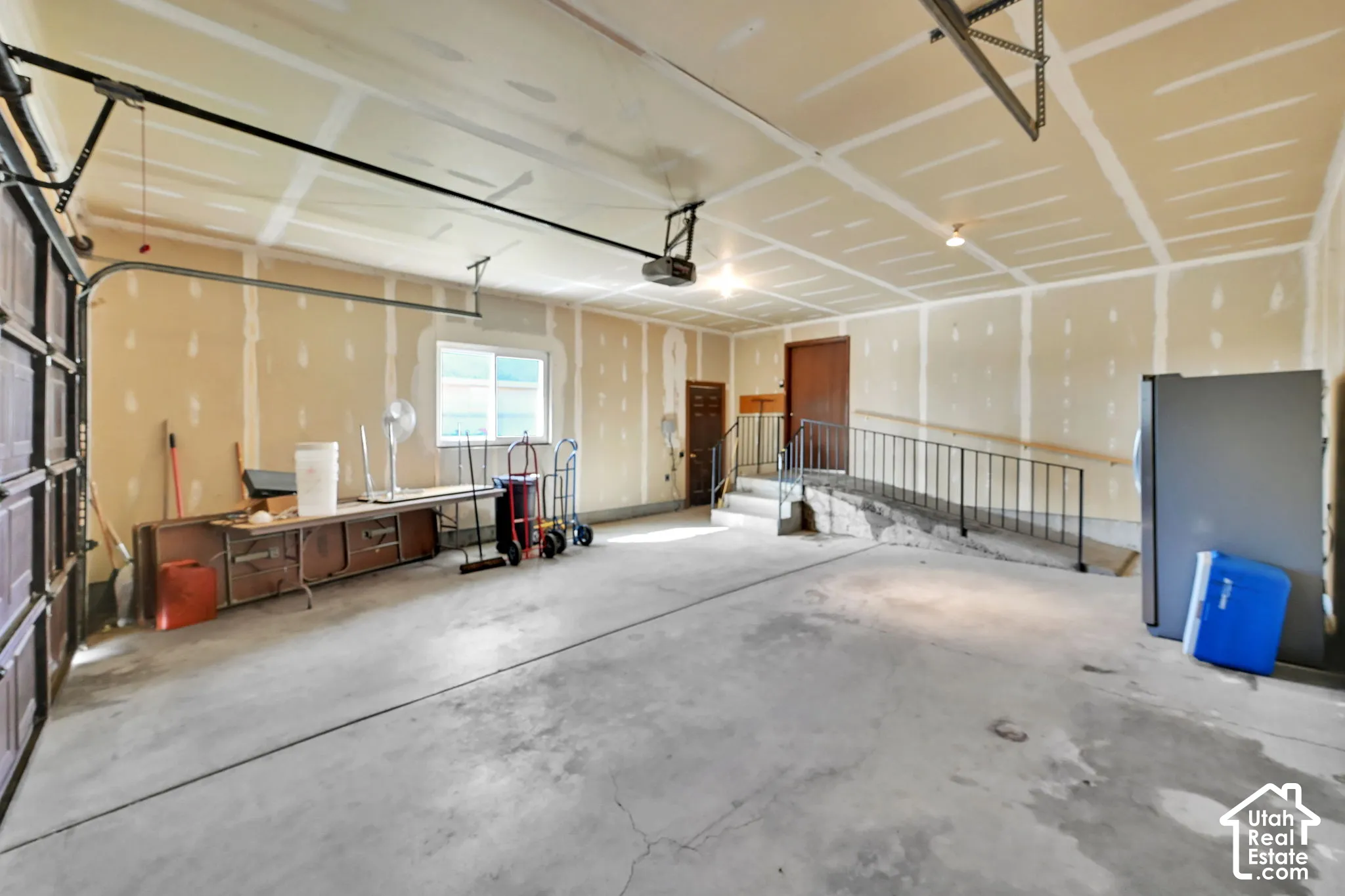 Spacious garage with concrete flooring, overhead lighting, and an overhead garage door