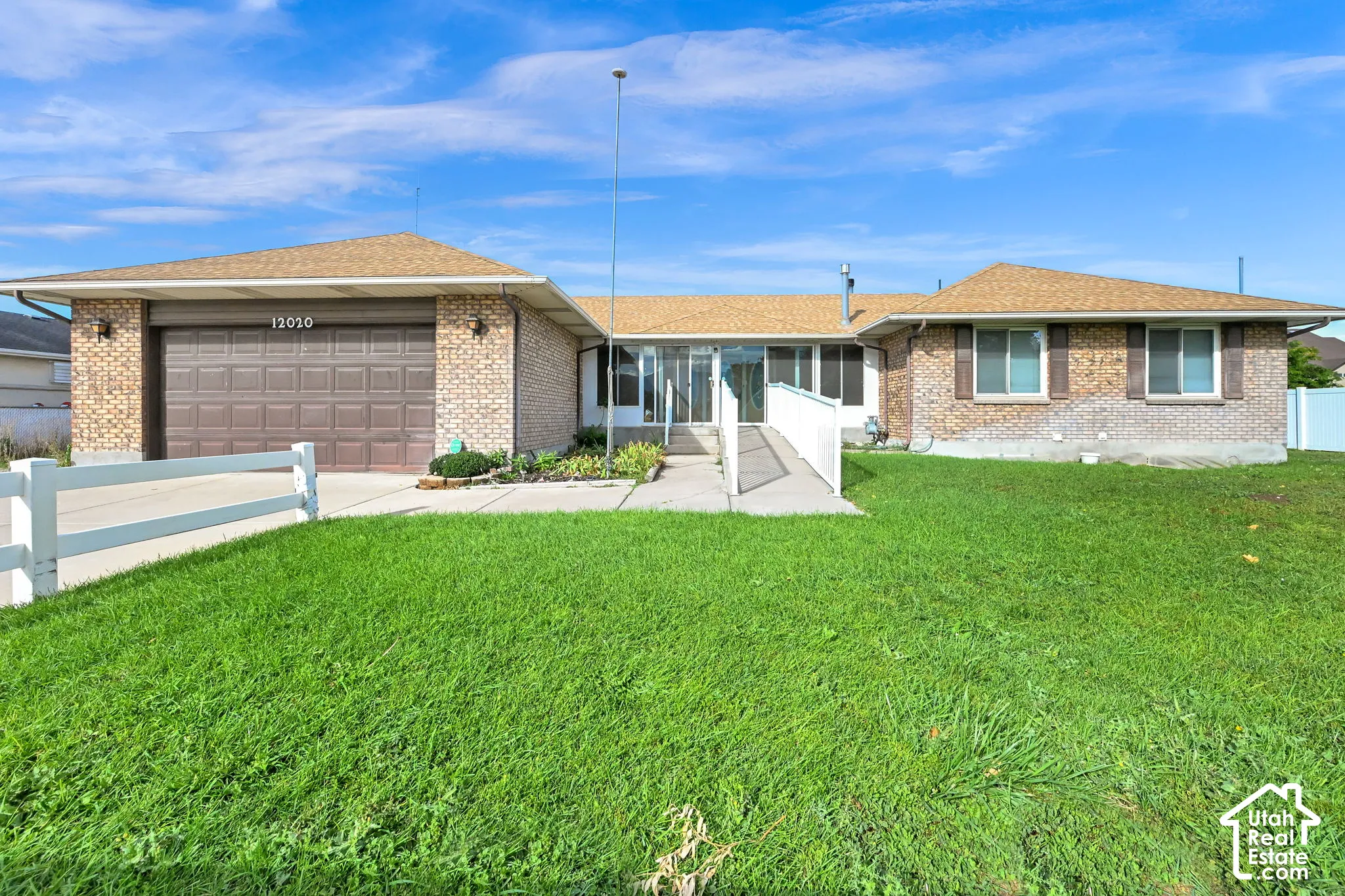 Brick exterior with a brown garage door, front lawn, and paved driveway