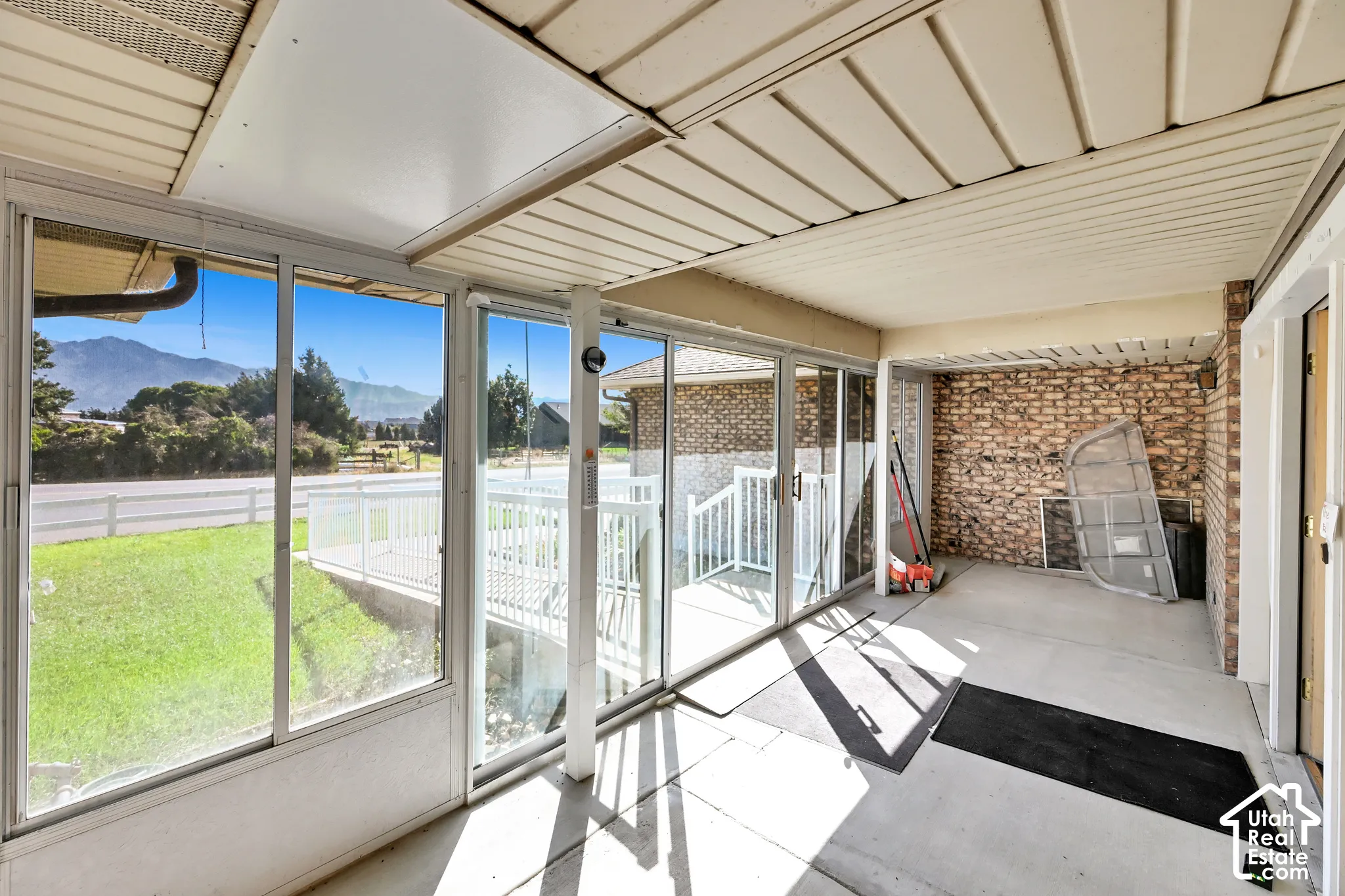 Enclosed patio featuring floor-to-ceiling windows, a mountain backdrop, a white railing, and a brick accent wall