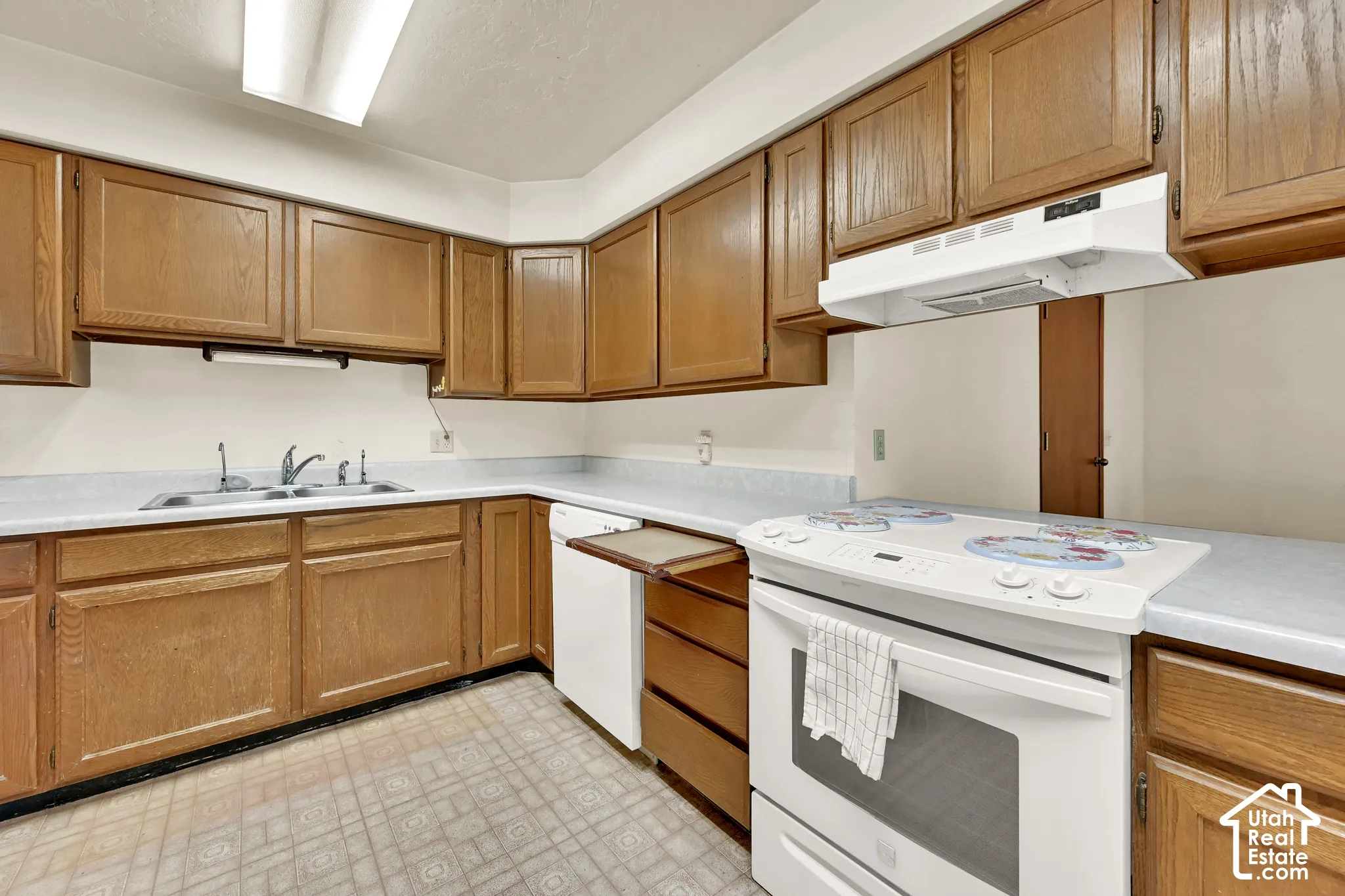 Kitchen featuring wood cabinetry, white appliances, and light-toned countertops