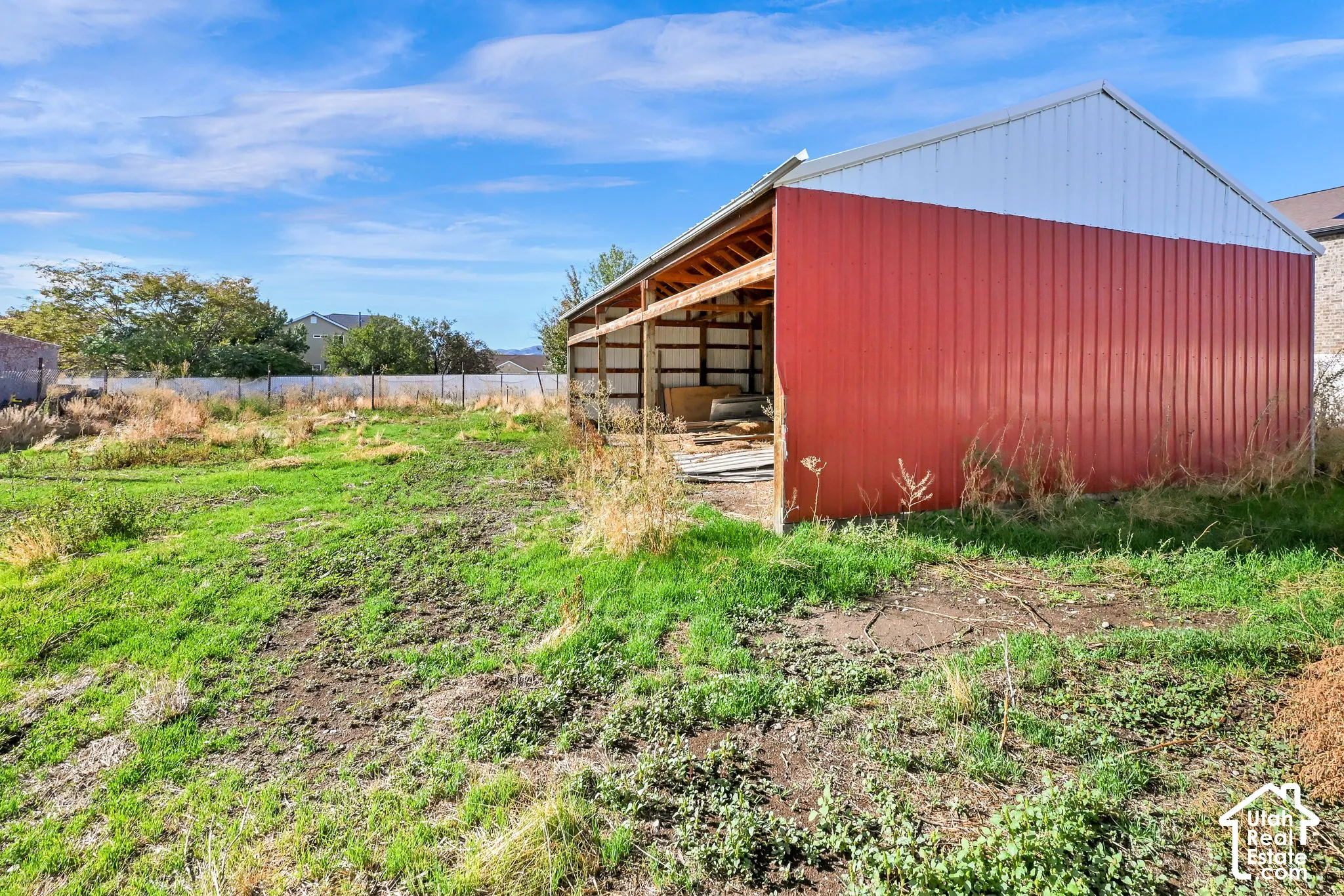 Red and white metal-sided barn with an open timber-framed section and a pitched roof