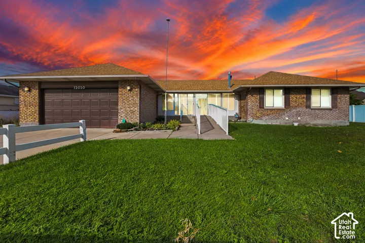 Brick exterior, attached garage, brown garage door, front lawn, white fence
