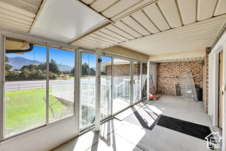 Enclosed patio featuring floor-to-ceiling windows, a mountain backdrop, a white railing, and a brick accent wall