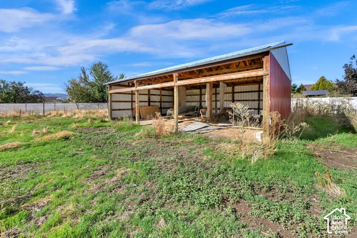 Open-air barn structure featuring a metal roof and red corrugated siding