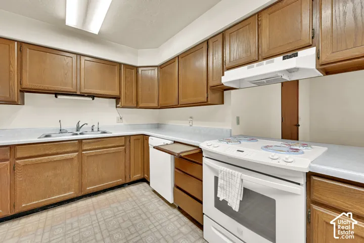 Kitchen featuring wood cabinetry, white appliances, and light-toned countertops