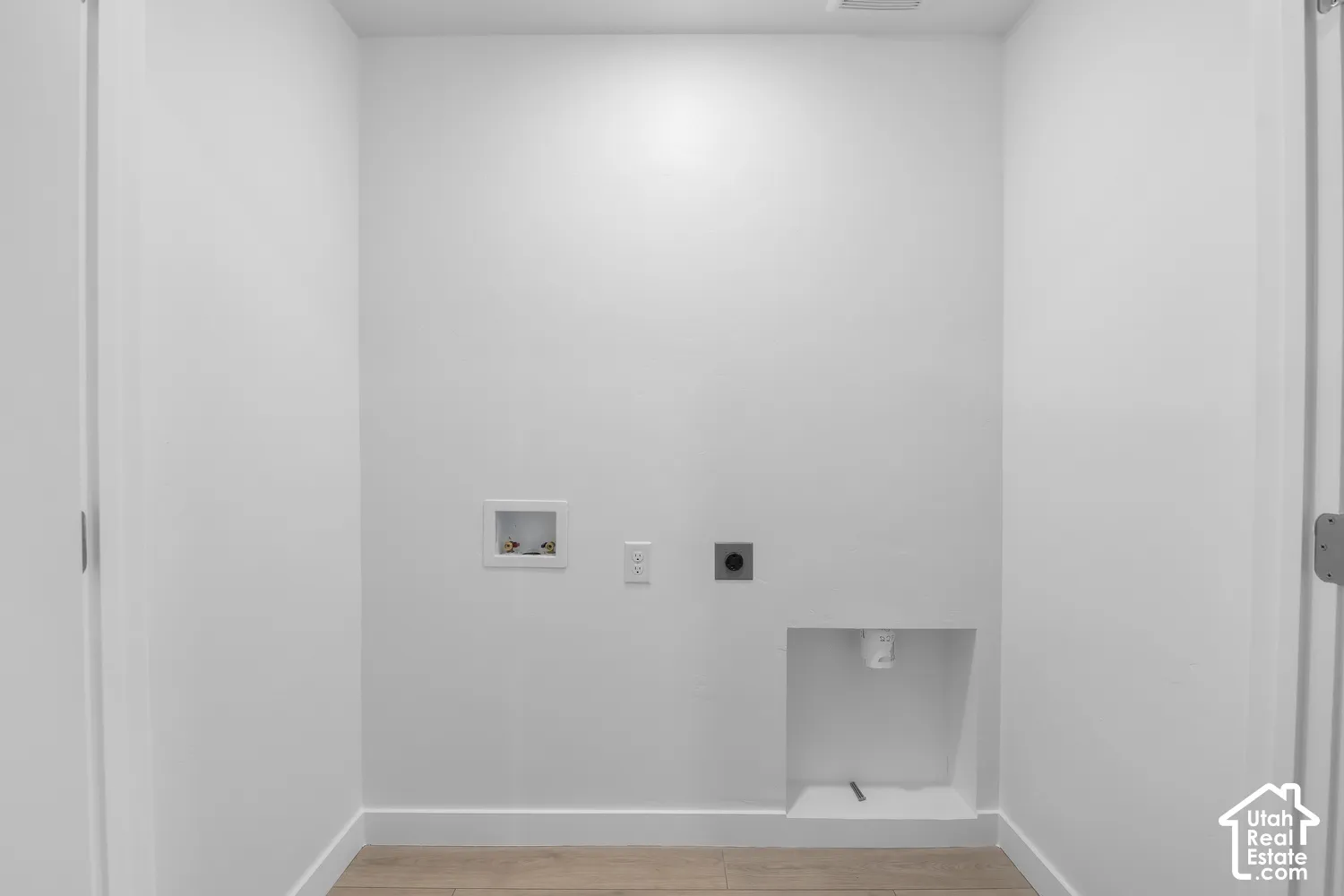 Dedicated laundry area with utility hookups and wood-finish flooring