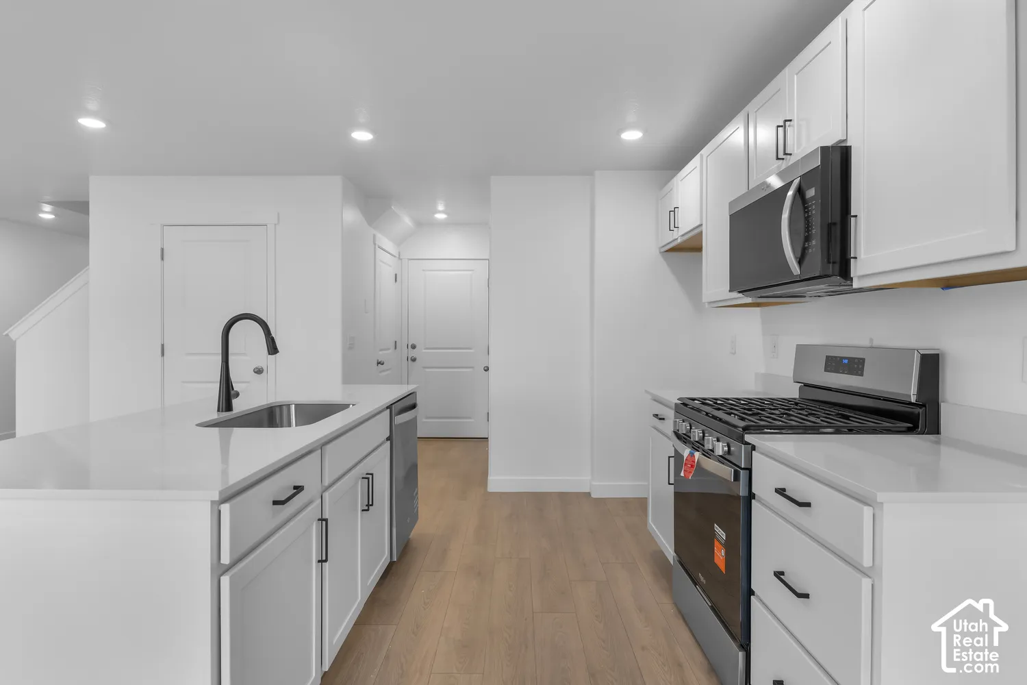 Kitchen featuring an island with an undermount sink, a matte black faucet, and white cabinetry