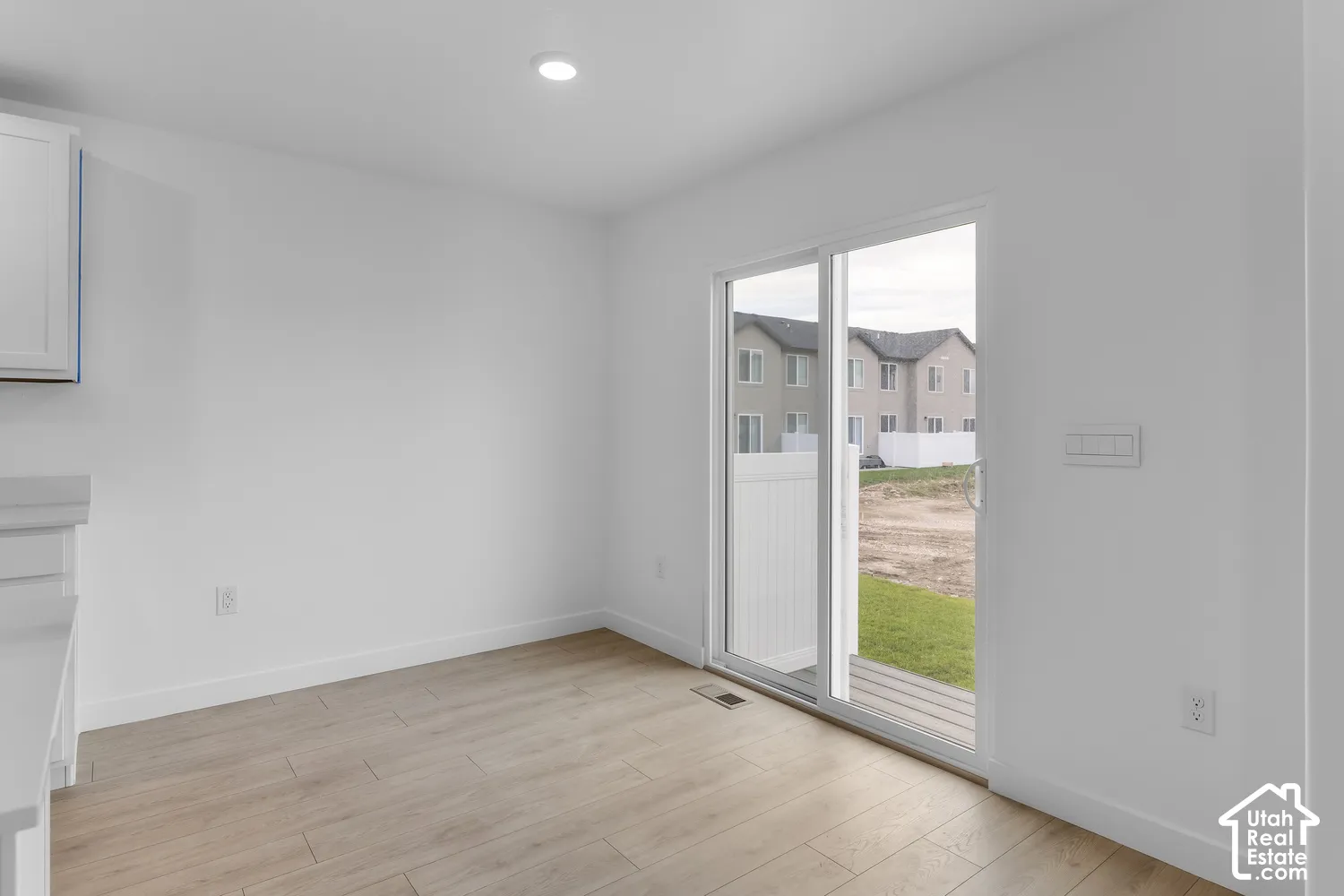 Wood-finish flooring, recessed ceiling lighting, and a sliding glass door to the exterior