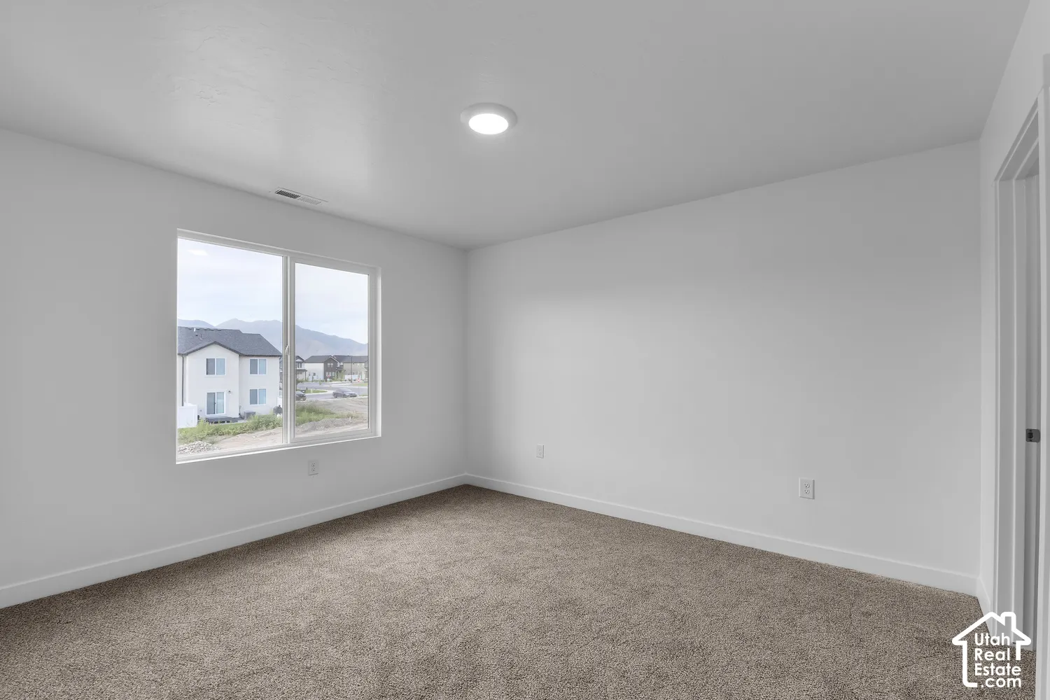 Recessed ceiling lighting, neutral carpet flooring, white painted walls, and a double-pane window