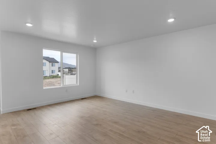 Recessed ceiling lighting, wood-finish flooring, white walls, and a large window