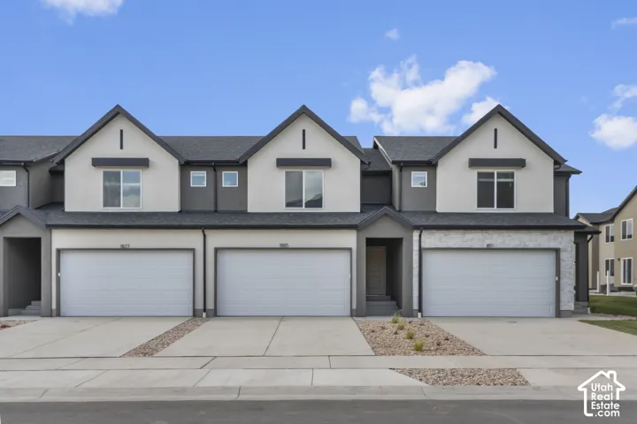 Modern townhome with gabled roofline, two-car garage, stucco exterior, and stone veneer accents