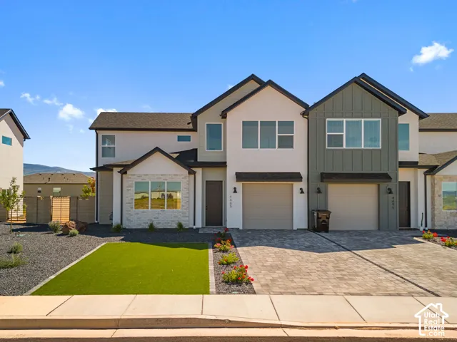 Contemporary exterior architecture with mixed material siding, paver driveway, artificial turf lawn, and integrated garage