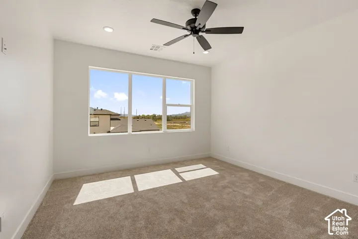Expansive window, neutral carpeting, recessed lighting, and a ceiling fan with integrated lighting