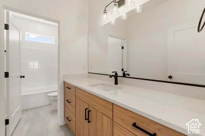 Dual-sink vanity with wood-finish cabinetry, light-toned countertop, and matte black hardware