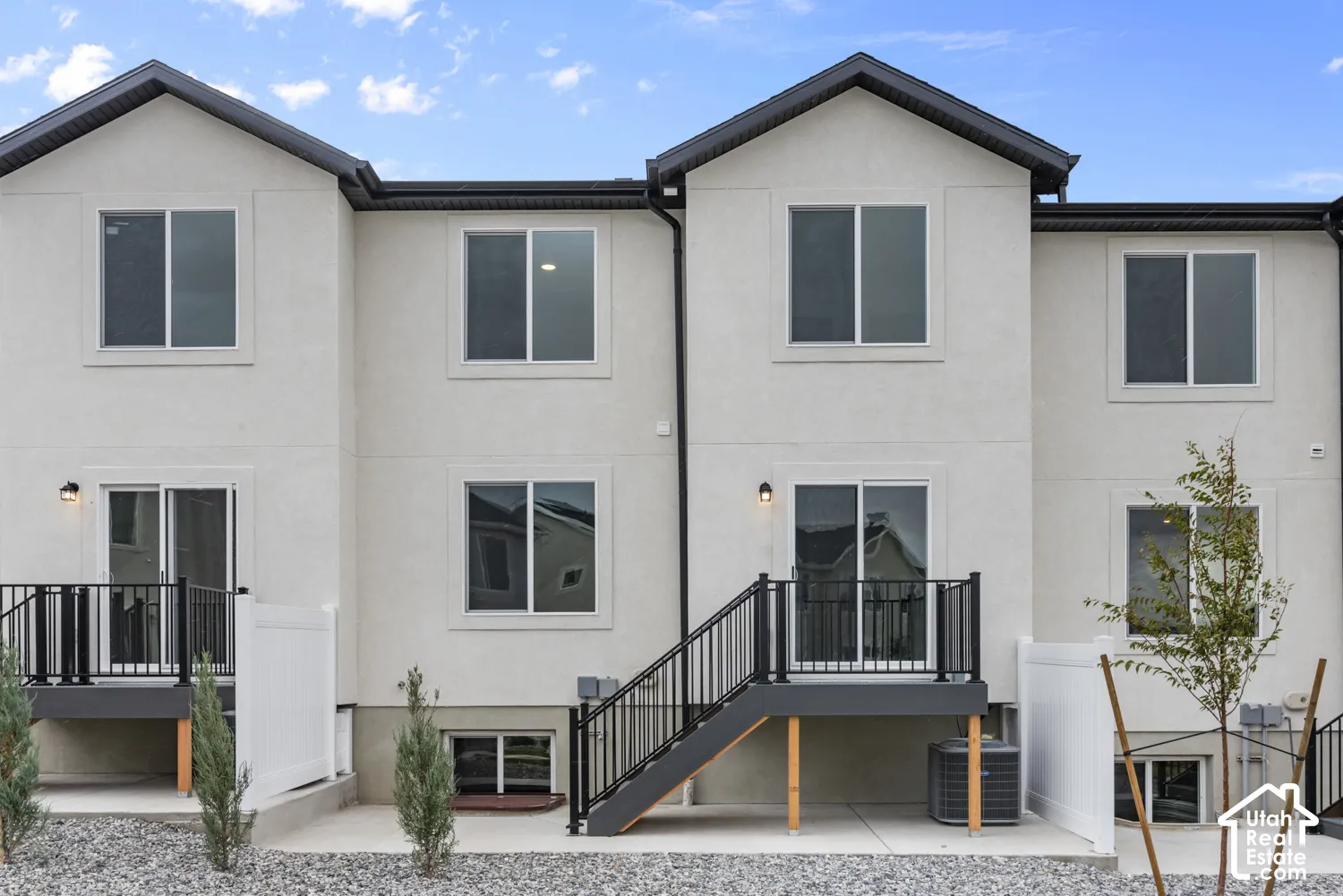 Stucco exterior with multiple windows, sliding glass doors, and a private balcony