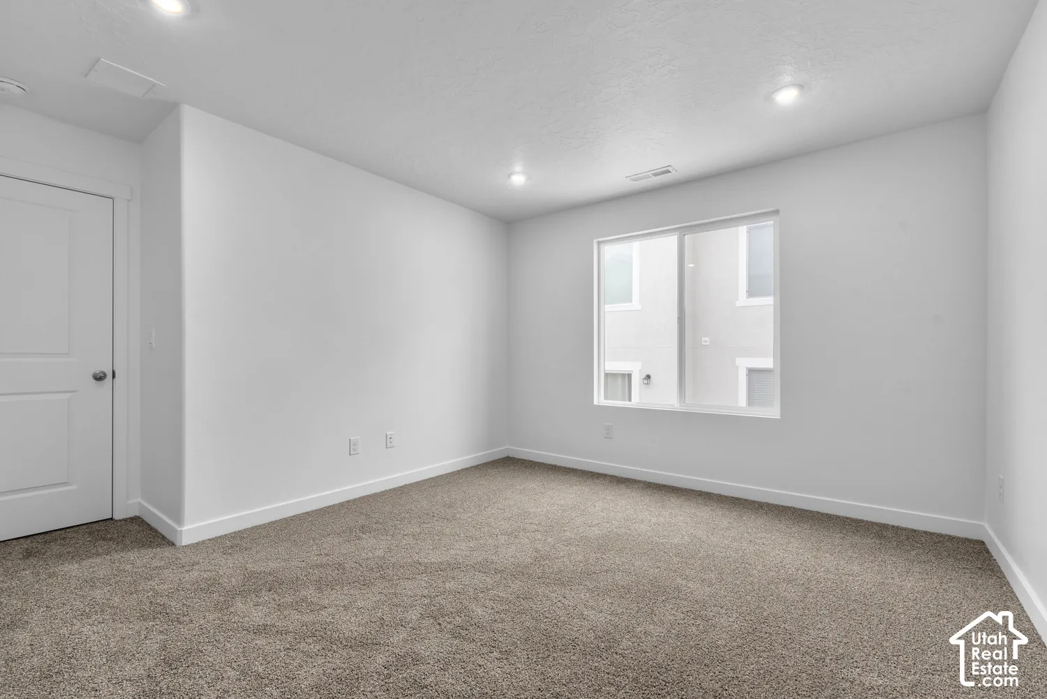Recessed ceiling lighting, white interior door with polished chrome hardware, double-pane window, and carpeted flooring