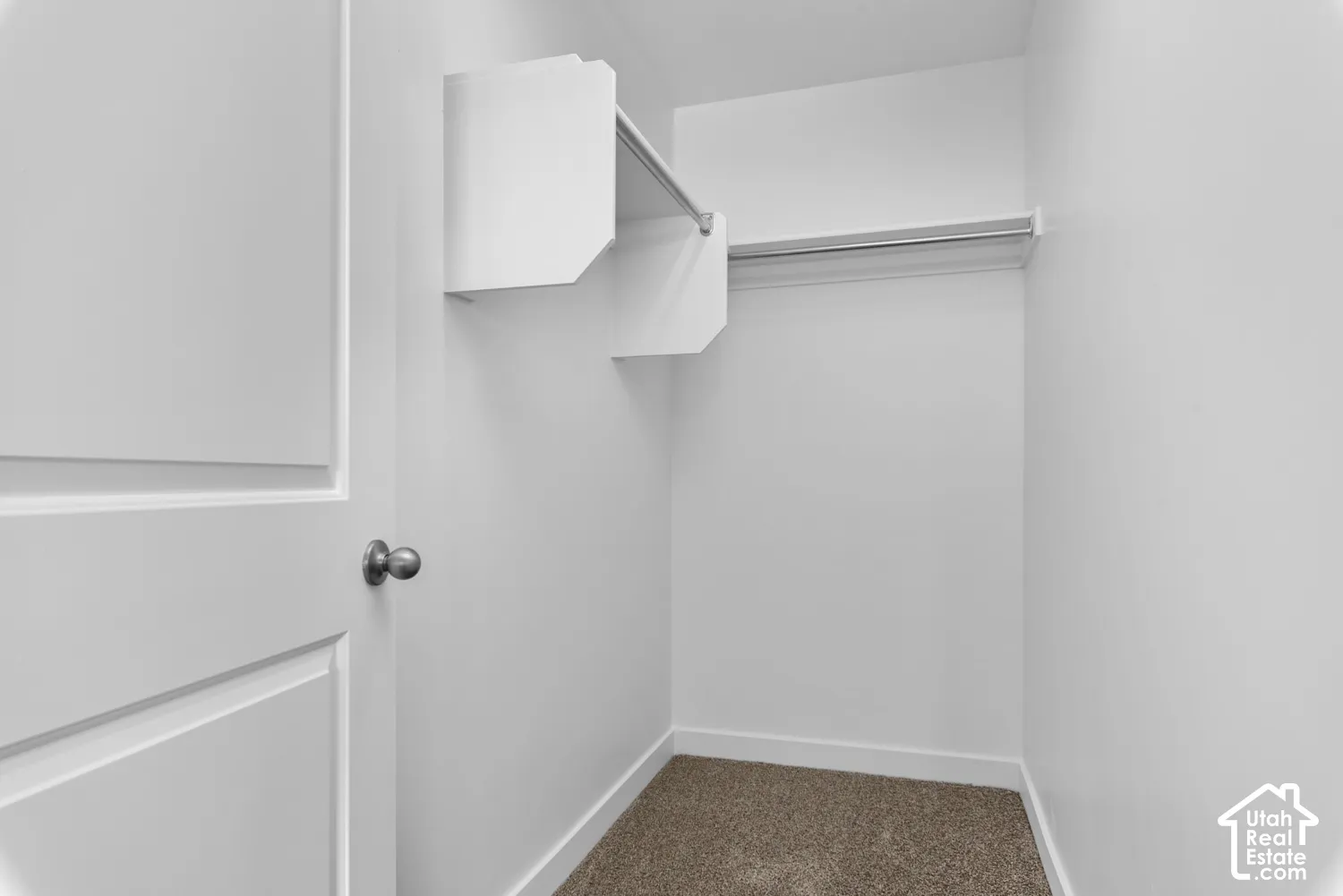 Recessed closet featuring white walls, a single hanging rod, and built-in shelving