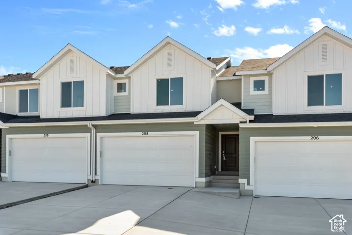 Multi-family exterior featuring vertical siding, horizontal lap siding, attached two-car garages, and asphalt shingle roofline