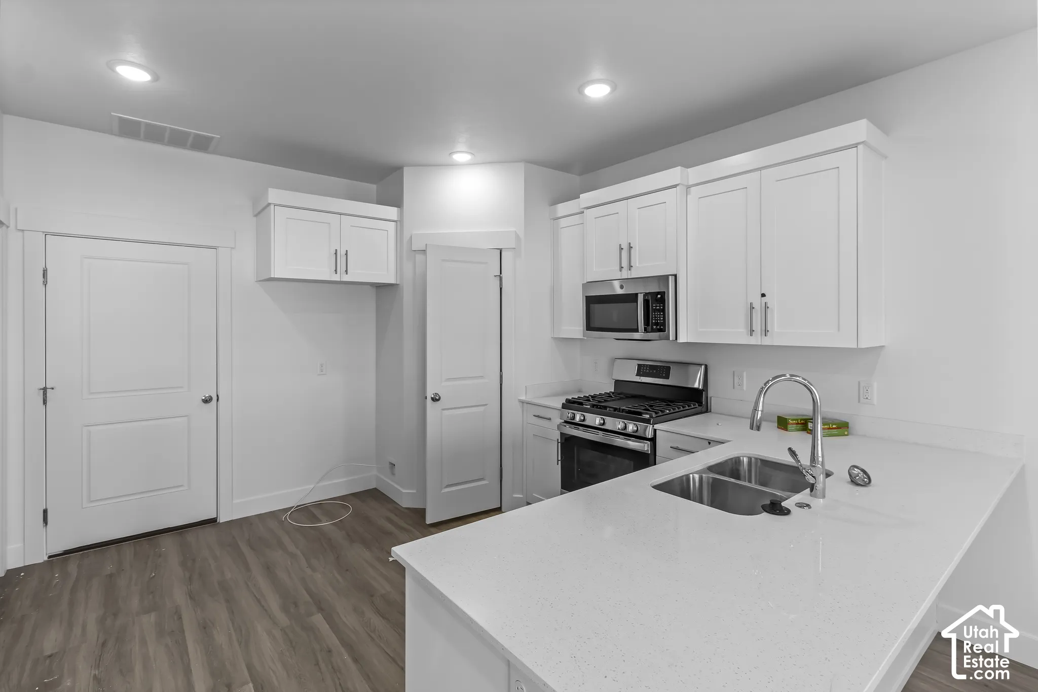 White shaker cabinetry, stainless steel appliances, quartz countertops, dual basin sink, and recessed lighting