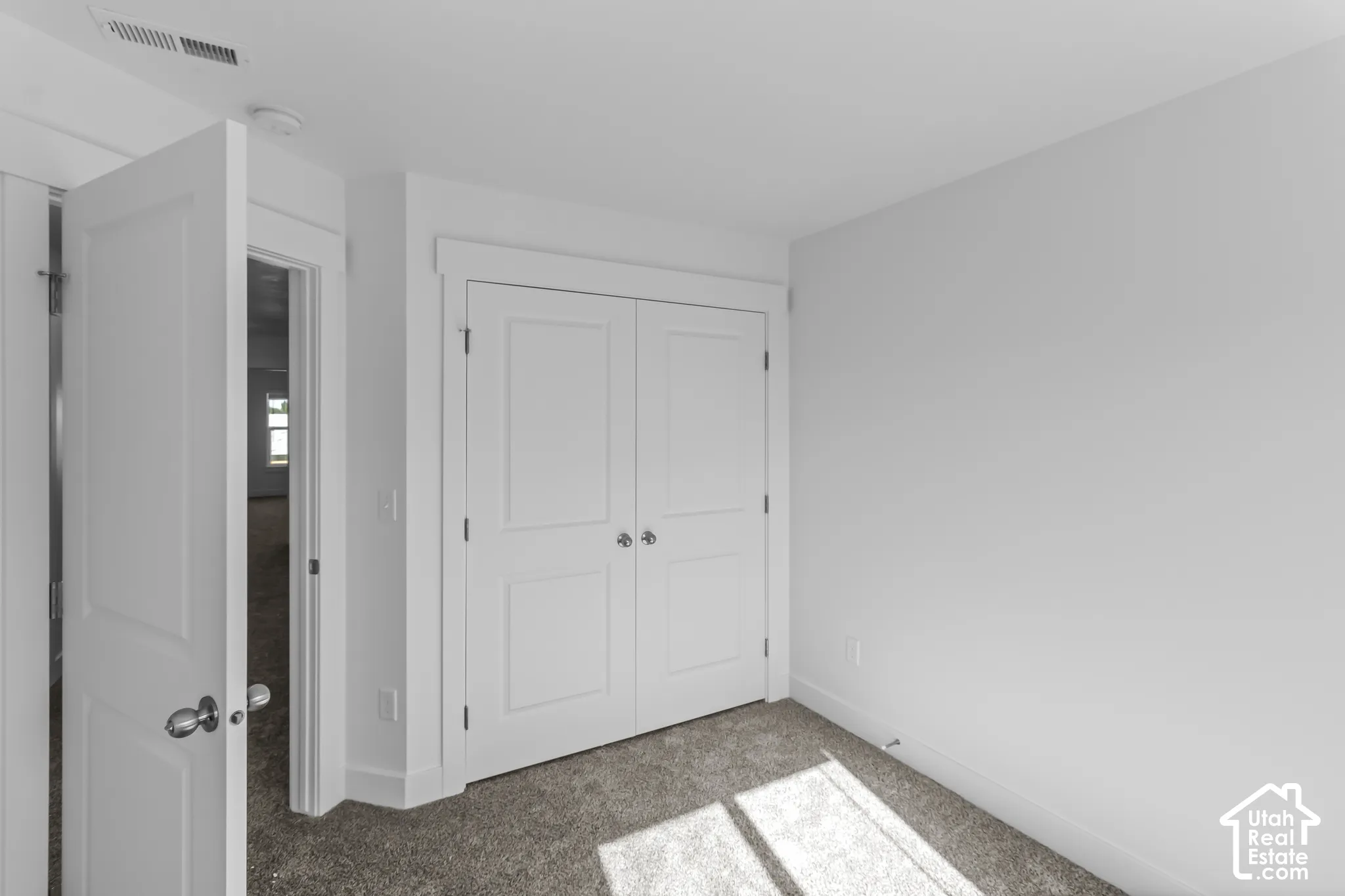 White interior doors, white baseboards, and neutral carpeting