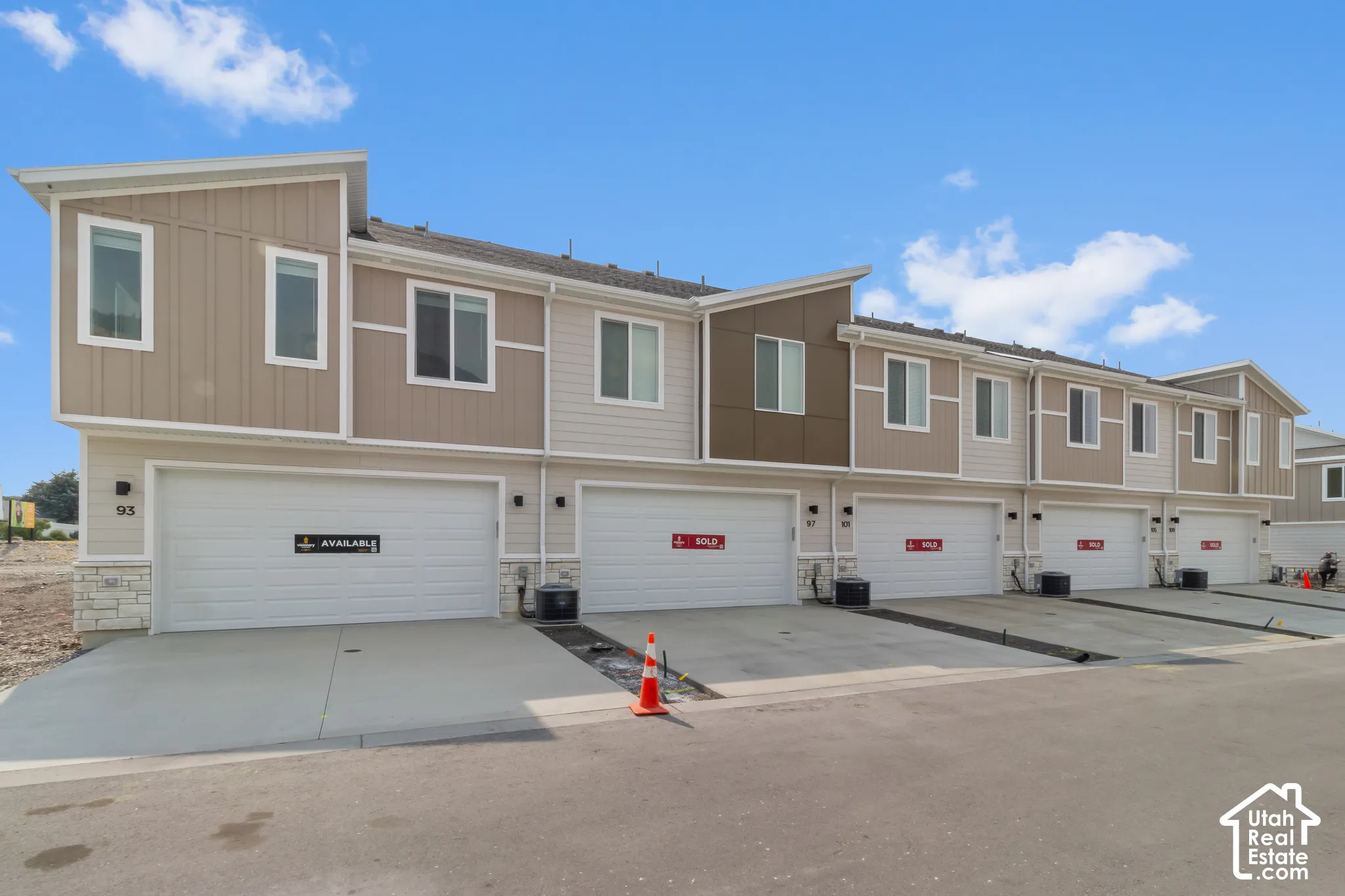 Contemporary townhome exterior with mixed material siding, white trim, and a prominent attached garage