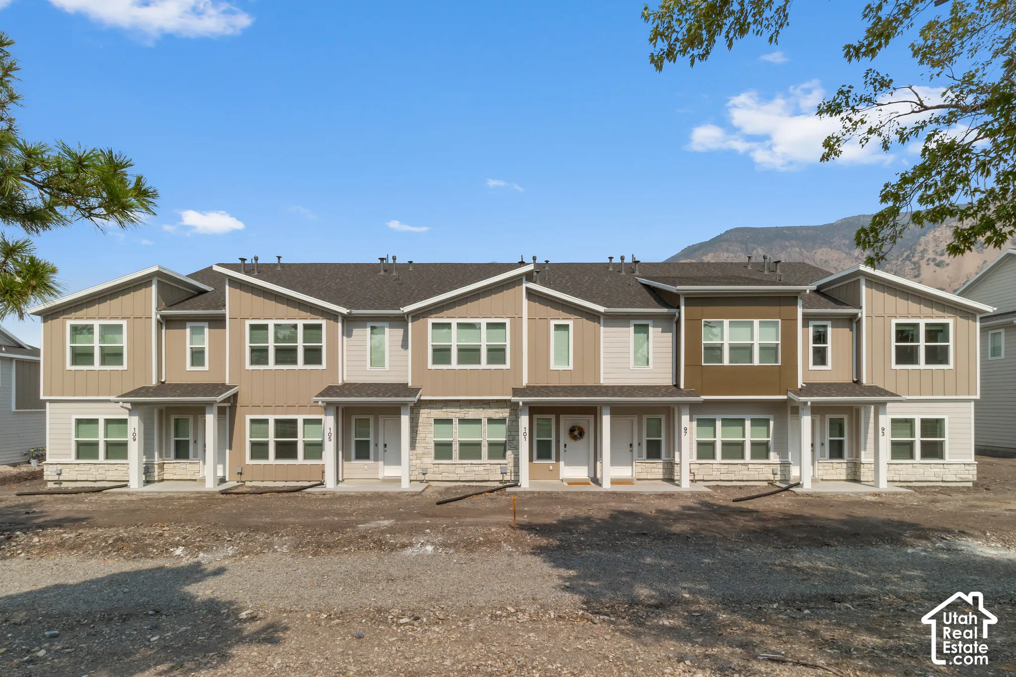 Contemporary multi-family building featuring a varied facade with horizontal and vertical siding, stone accents, and covered entryways