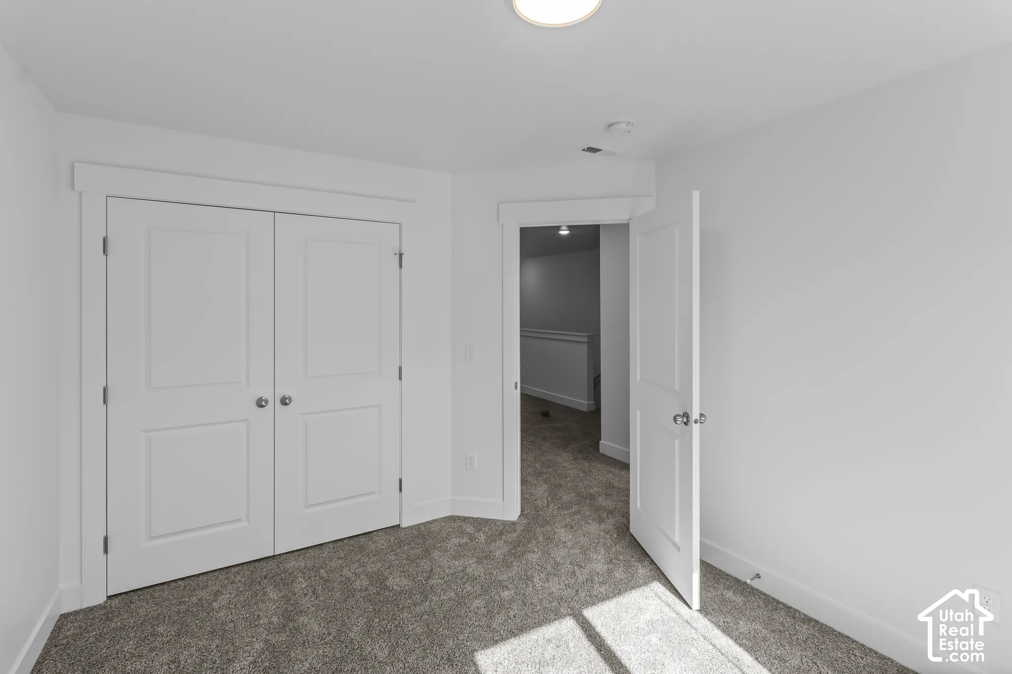 Neutral wall color, wall-to-wall carpeting, double closet doors, white trim, and overhead lighting