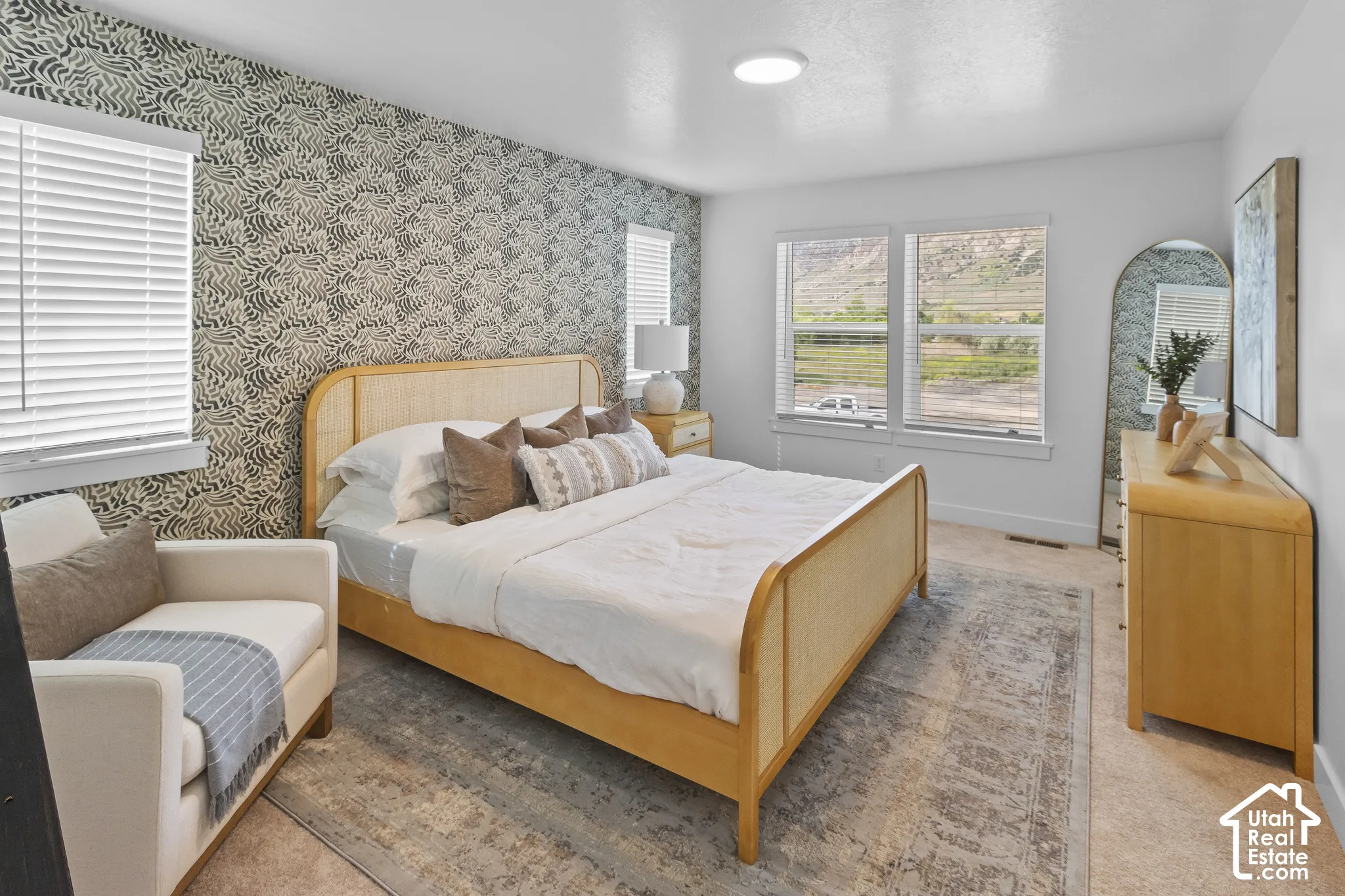 Accent wall with a botanical pattern, two windows with blinds, recessed ceiling light, and wood-finish flooring